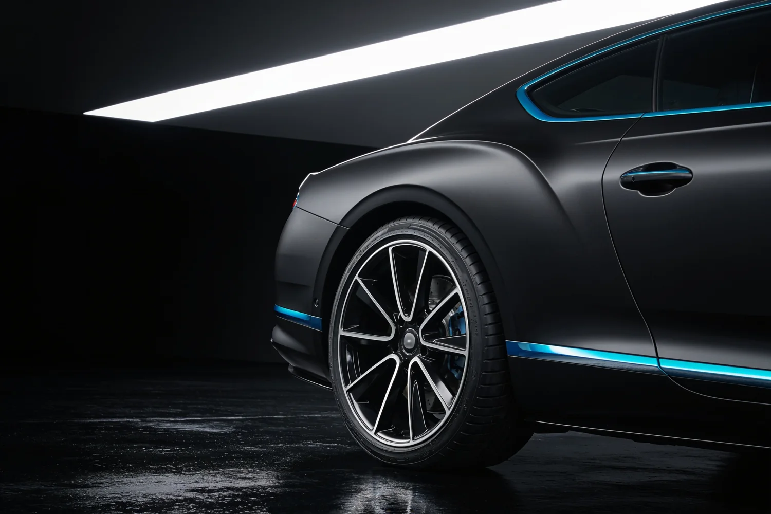 Graphite touring car and polished wheel under studio lighting.